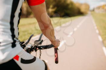 Male cyclist in sportswear, cycling on asphalt road. Male sportsman rides on bicycle. Workout on bike path