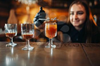 Female bartender prepares alcoholic coctail. Alcohol drink preparation. Barman working at the bar counter in pub