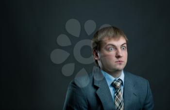 Young surprised businessman in suit and tie on black background. Thoughtful businessperson, male manager shocked