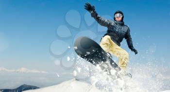 Male snowboarder, dangerous downhill in action, front view. Snowboarding is an extreme winter sport. Man on snowboard in jump