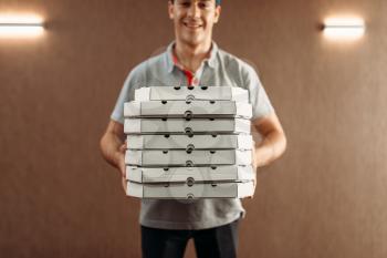 Pizza delivery man with boxes, delivering service. Courier from pizzeria holds cardboard package indoor