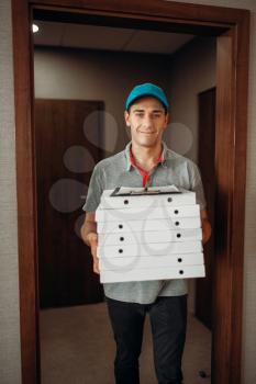 Delivery man with fresh pizza in carton boxes, delivering service. Courier from pizzeria holds cardboard packages indoors