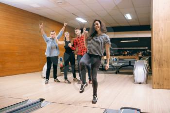 Female bowler throws ball on lane, strike shot. Bowling alley teams playing the game in club, active leisure