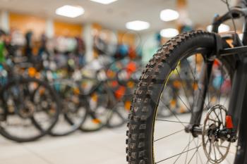 Mountain bicycle in sports shop, focus on front wheel, nobody. Summer active leisure, showcase with bikes, cycle sale, professional biking equipment