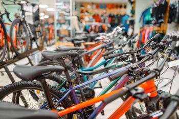 Rows of mountain bicycles in sports shop, focus on seat, nobody. Summer active leisure, showcase with bikes, cycle sale