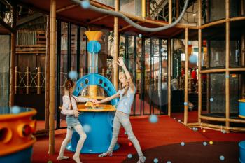 Two little girls plays air gun machine in children game center. Excited childs having fun on playground indoors. Kids playing in amusement centre
