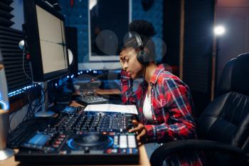 Female sound operator working at the remote control panel in audio recording studio. Musician at the mixer, professional music mixing