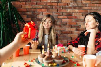 Group of highschool students give each other gifts. Youth at the table in the flat, home party, birthday celebration