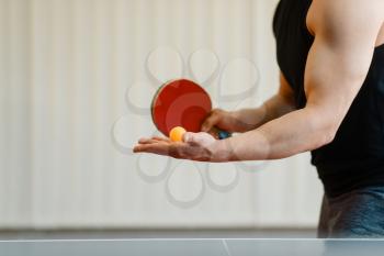 Man with ping pong racket preparing to hit a ball, workout indoors. Male person in sportswear, training in table tennis club