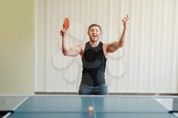 Man with racket in hand wins ping pong tournament indoors. Male person in sportswear, training in table tennis club