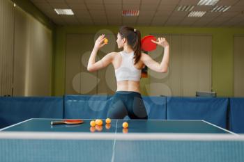Attractive woman with racket poses at the ping pong table indoors. Female person in sportswear, training in table tennis-club