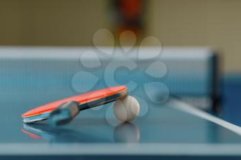 Ping pong racket and ball on game table with net, nobody, closeup view. Table-tennis club, tennis concept, ping-pong symbol