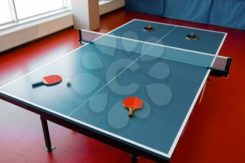 Four ping pong rackets on game table with net, nobody, top view. Table-tennis club, tennis concept, ping-pong symbol