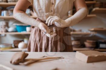 Female artisan hands covered with dried clay, pottery workshop interior on background. Woman molding a bowl. Handmade ceramic art, tableware making