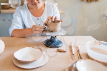 Female potter skins pot, pottery workshop. Woman molding a bowl. Handmade ceramic art, tableware from clay