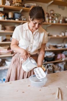 Female potter washes a foarm, pottery workshop. Woman cleans equipment after working. Handmade ceramic art, tableware from clay