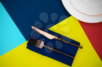 Table setting, silverware and plate closeup, top view, nobody. Banquet decoration, colorful tablecloth and napkins, tableware outdoors