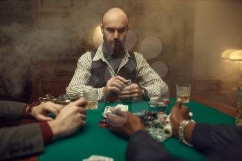 Poker players with cards and chips in casino. Games of chance addiction, gambling house. Men leisures with whiskey and cigars