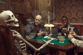 Male poker players and skeleton at gaming table with green cloth, fun, casino. Games of chance addiction, risk, gambling house. Men leisures with whiskey and cigars