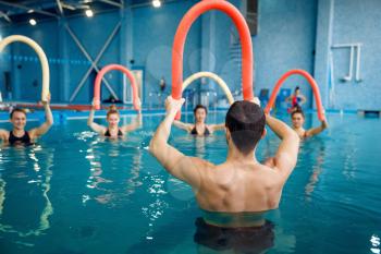 Male instructor and female group, aqua aerobics training in the pool. Man and women in the water, sport fitness workout