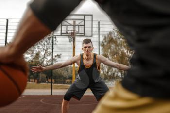 Two basketball players on outdoor court, active leisure. Male athletes in sportswear play the game on streetball training
