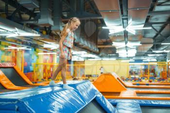 Adorable girl jumping on kids trampoline, playground in entertainment center. Play area indoors, playroom
