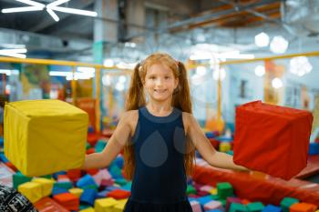Adorable little girl playing with soft cubes, playground in entertainment center. Play area indoors, playroom
