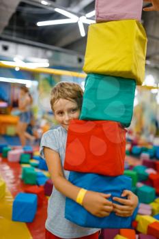Happy little boy playing with soft cubes, playground in entertainment center. Play area indoors, playroom