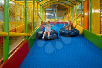 Little children rides on tubing, playground in entertainment center. Play area indoors, playroom