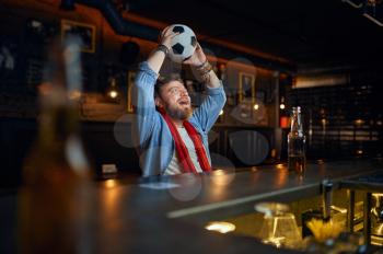 Football fan with ball sitting at the counter in bar. One male person resting in pub, human emotions, leisure activity, game or match broadcast