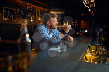 Bearded man sitting at the counter in bar. One angry male person in pub, human emotions and leisure activities, depression, stress relief