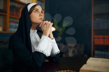 Young nun in a cassock prays crossed her arms. The sister in the monastery, religion and faith, religious people