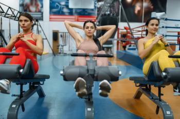 Group of women doing abs exercise in gym, front view. People on fitness workout in sport club, athletic girls in sportswear on training indoors
