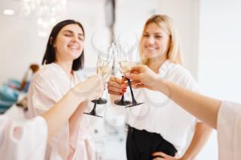 Group of happy girlfriends clink glasses in beauty salon. Professional beautician service. Female customers celebrate the meeting in spa studio