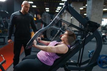Overweight woman with trainer doing exercise in gym, fitness training with instructor. Female person struggles with excess weight, aerobic workout against obesity