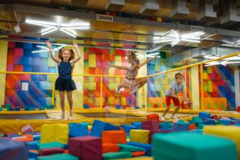 Little children having fun on kids trampoline, playground in entertainment center. Play area indoors, playroom