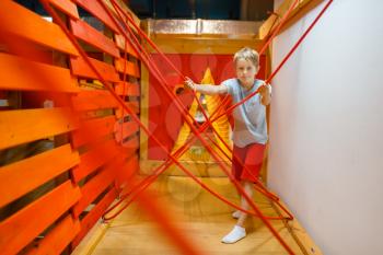 Little boy playing in rope labyrinth, playground in entertainment center. Play area indoors, playroom