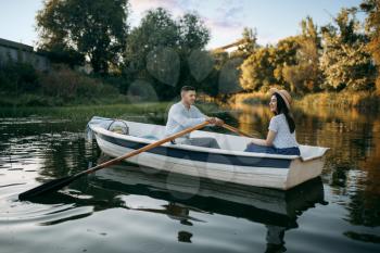 Love couple boating on lake at summer day, water reflection. Romantic data, boat ride, man and woman walking along the lake
