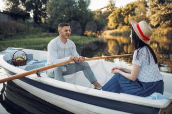 Love couple boating on lake at summer day. Romantic meeting, boat ride, man and woman walking along the river