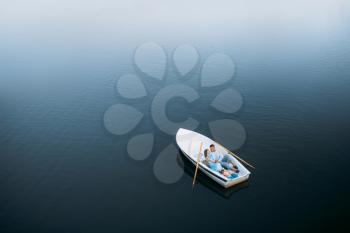 Love couple lying in a boat on silent lake, top view. Romantic meeting, boating trip, man and woman walking along the river