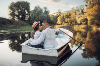 Happy love couple boating on lake at summer day. Romantic date, boat trip, man and woman walking along the river