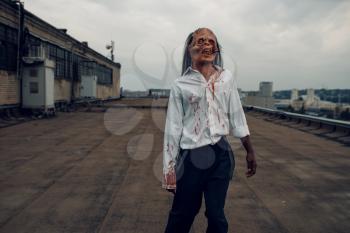 Scary zombie on the roof of abandoned building, deadly chase. Horror in city, creepy crawlies attack, apocalypse