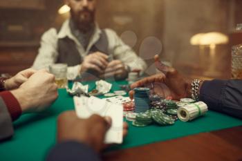 Male poker players at gaming table with green cloth, casino. Games of chance addiction, risk, gambling house. Men leisures with whiskey and cigars
