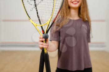 Female person shows squash racket and ball. Girl on game training, active sport hobby on court