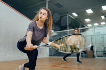 Two female players with squash racket playing on court. Girl on game training, active sport hobby.