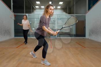 Two female players with rackets, squash game on court. Girls on training, active sport hobby, fitness workout for healthy lifestyle
