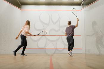 Two female players with rackets, squash game on court. Girls on training, active sport hobby, fitness workout