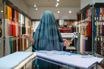 Woman wrapped in fabric, textile store. Seamstress choosing material for sewing, female tailor in shop, dressmaker