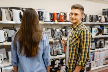 Young couple at the shelf with electric kettles in electronics store. Man and woman buying home electrical appliances in market