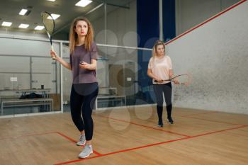 Two female players with squash racket playing on court. Girl on game training, active sport hobby, fitness workout for healthy lifestyle